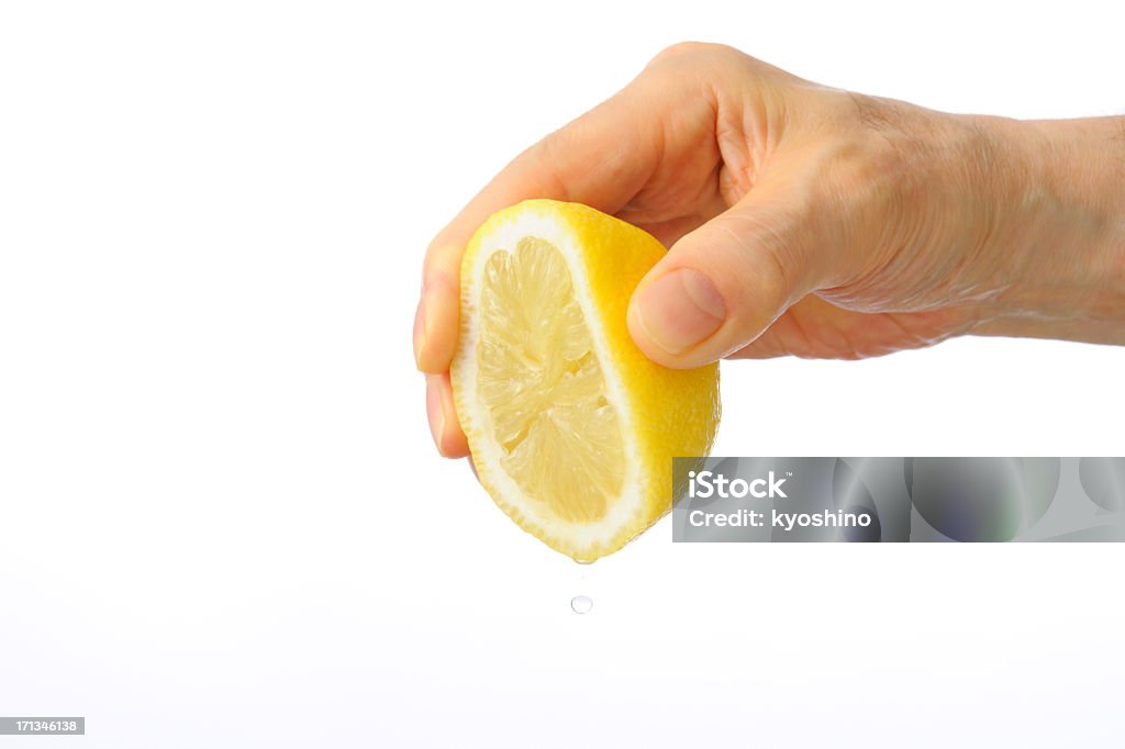 Isolated shot of hand squeezing a lemon against white background Close-up shot of hand squeezing a lemon isolated on white background. Lemon - Fruit Stock Photo