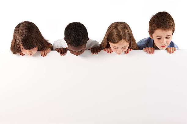 Group of multi ethnic children holding a white board Group of children standing over a blank board. Isolated on a white background. kids using smart board stock pictures, royalty-free photos & images
