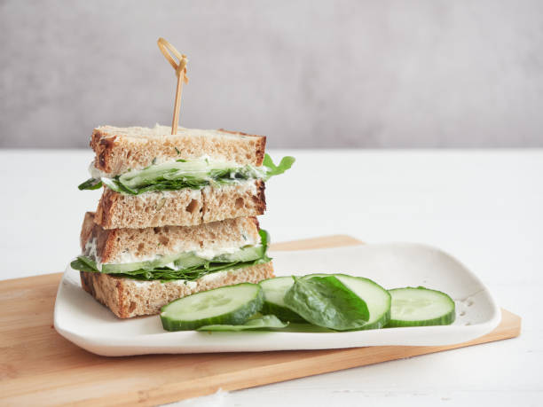 istock cucumber and green spinach sandwich, cut in half and stacked on white platter 1713468290