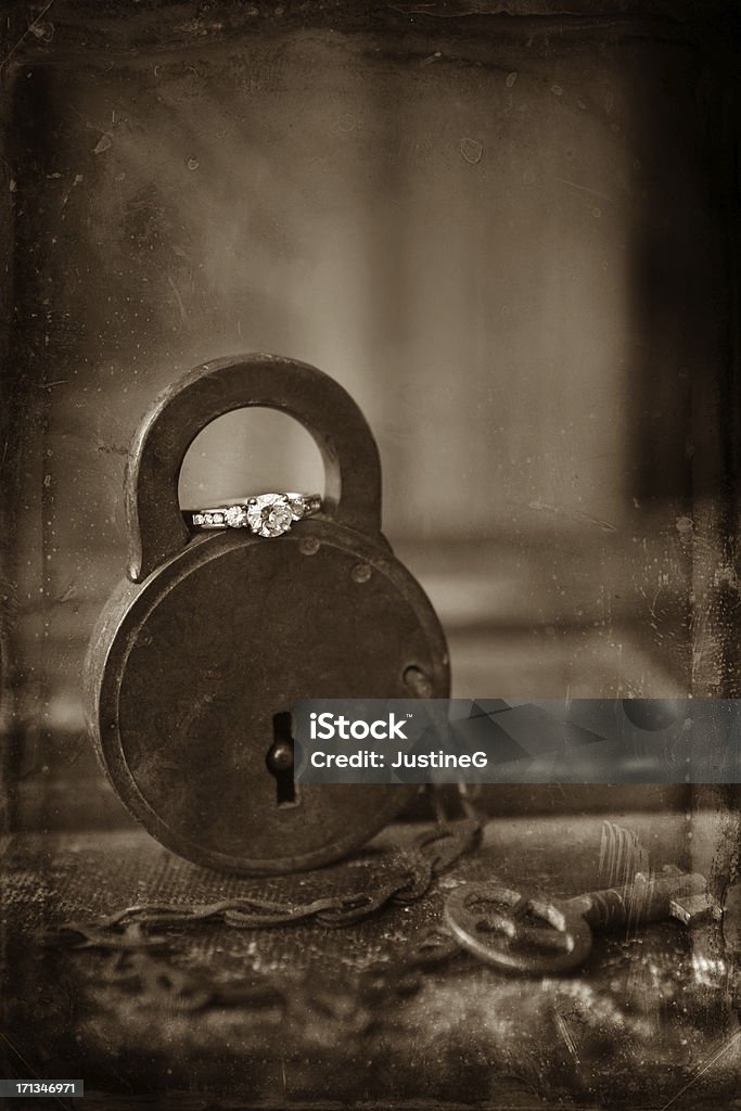 engaged A fine art image of a diamond engagement ring on an antique lock in sepia tone with dust and scratches on the image. Antique Stock Photo