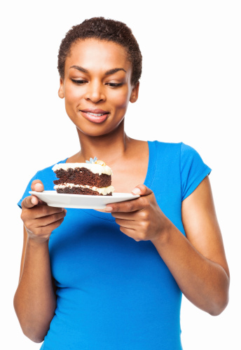 Hungry African American woman looking at delicious plate of pastry. Vertical shot. Isolated on white.