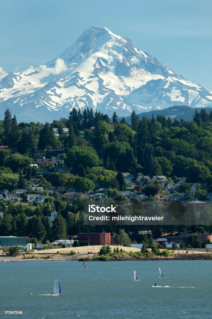 Snow covered Mount Hood and Columbia River Mt. Hood rises behind the town of Oregon's Hood River in the Columbia River. Windsurfers and kiteboarders zip in the wind swept river. Columbia River Stock Photo