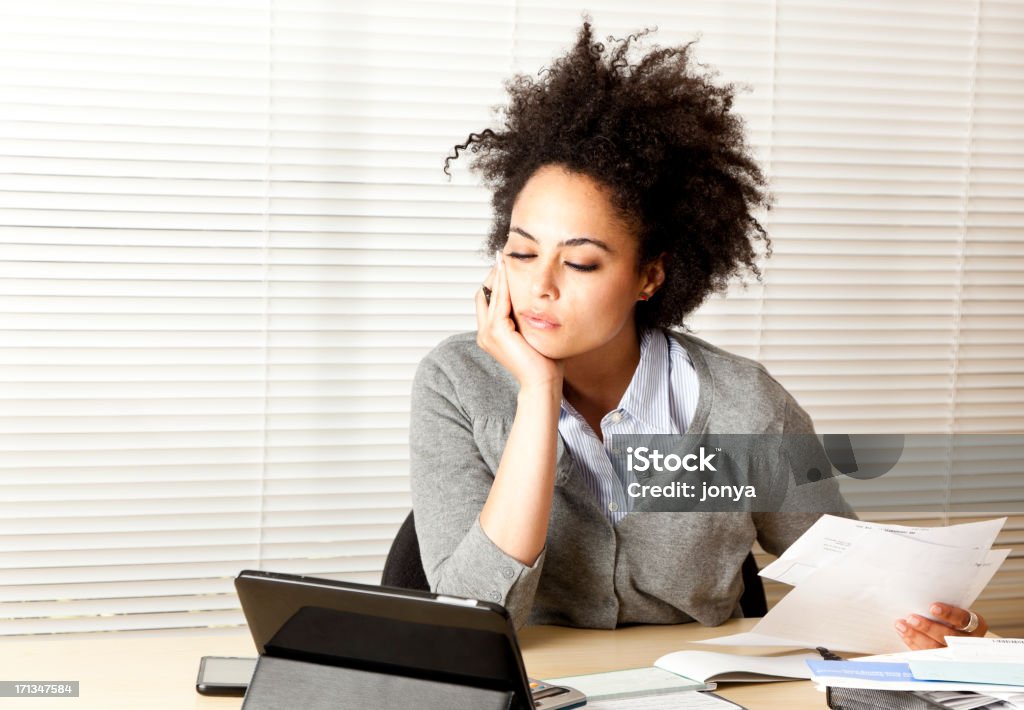 curly-haired woman doing paperwork "mixed race curly haired woman in front of touch screen tablet, doing bookkeeping - in home office" Computer Stock Photo