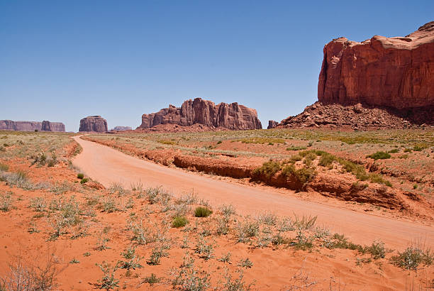 Dirt Road Leading to Merrick Butte A dirt road leads toward Merrick Butte at Monument Valley Tribal Park in Arizona, USA. jeff goulden monument valley stock pictures, royalty-free photos & images