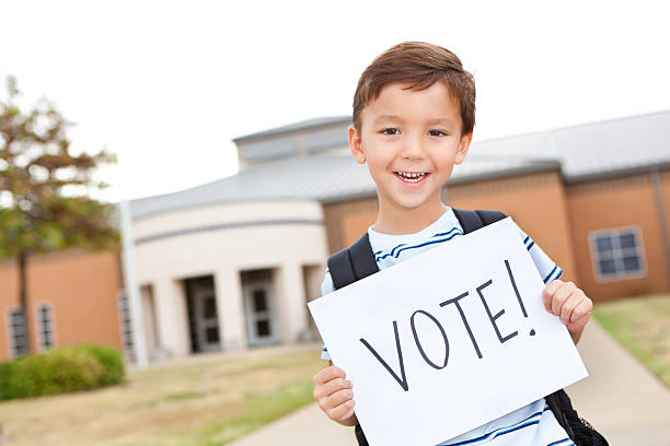 istock Elementary student holding a Vote sign in front of school 171349291