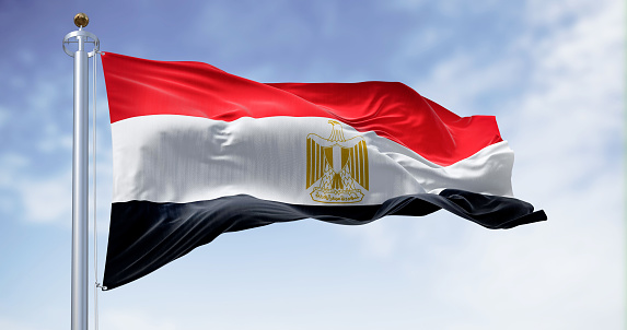 National flag of Egypt waving in the wind on a clear day. Horizontal red, white and black bands. Egyptian eagle emblem centered in white band. 3d illustration render. Fluttering fabric
