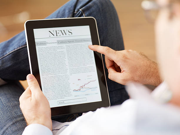 uomo di leggere il giornale su digital tablet - newspaper reading holding paper foto e immagini stock