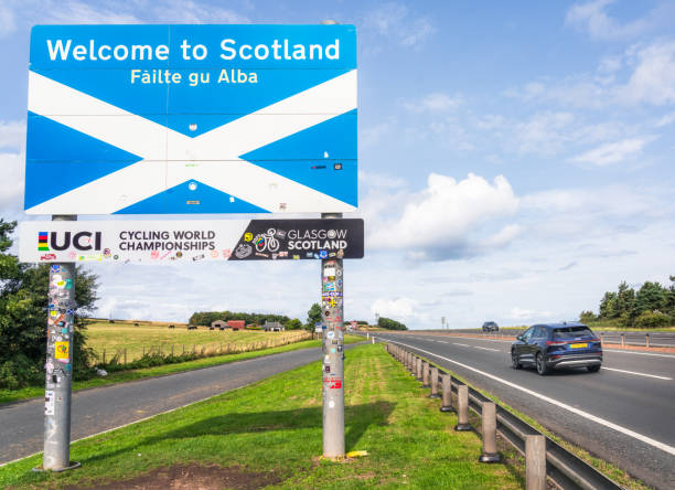 A1 Road, UK - A car passing the sign marking the Scottish border with England near Berwick.