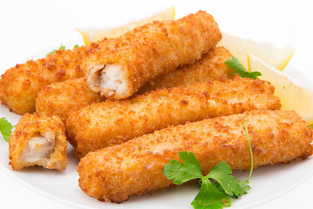 Fish fingers A pile of ready to eat fish fingers on a white plate with a white background fish stick stock pictures, royalty-free photos & images