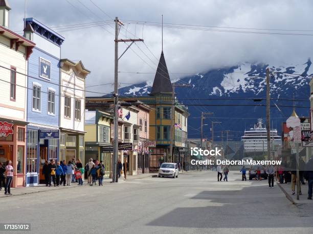 Downtown Skagway Tourists With Snow And Cloud Covered Mountains Background Stock Photo - Download Image Now