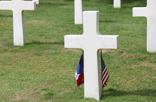 Cmemetry with white crosses on graves and flags of USA and France