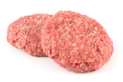 Two uncooked angus beef burgers on a white background.