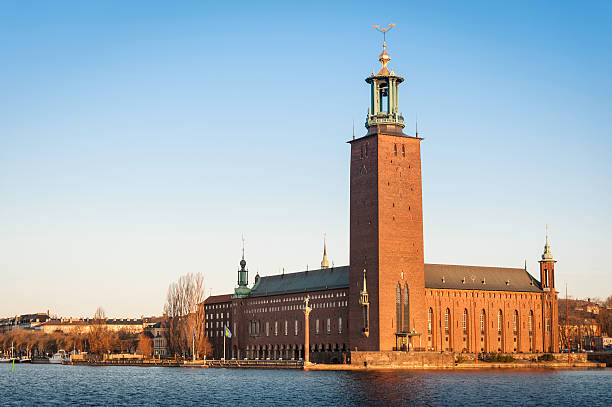 Stockholm Stadshuset City Hall sunrise Sweden "Warm early moring sunlight of daybreak illuminating the historic tower of Stockholm City Hall, Stadshuset, at its iconic waterfront location on Kungsholmen island reflecting in the still waters of Riddarfjarden in the heart of Sweden's picturesque capital city. ProPhoto RGB profile for maximum color fidelity and gamut." kungsholmen town hall photos stock pictures, royalty-free photos & images