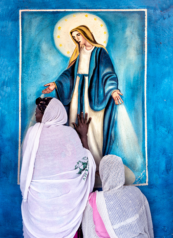 Lalibela. Ethiopia-july 26-2019: Two Orthodox Christian women venerate the Virgin Mary on Saint Gabriel's Day in Lalibela.  \nThe 11 medieval monolithic cave churches of this 13th-century 'New Jerusalem' are situated in a mountainous region in the heart of Ethiopia near a traditional village with circular-shaped dwellings. Lalibela is a high place of Ethiopian Christianity, still today a place of pilmigrage and devotion.