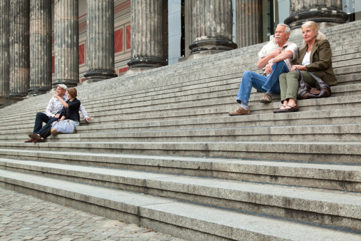 Senior and young couple sitting on staircase in Berlin, Germany. Shallow DOF with selective focus on senior couple on the right.