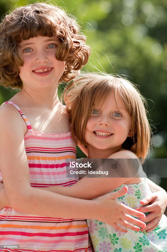 Color Retrato de feliz abrazando dos hermanas en entorno al aire libre - Foto de stock de 6-7 años libre de derechos