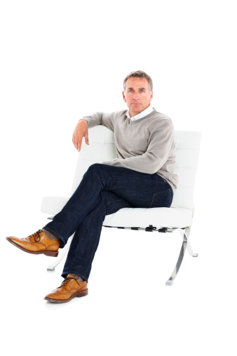 Portrait of confident mature guy sitting on a chair isolated over white background