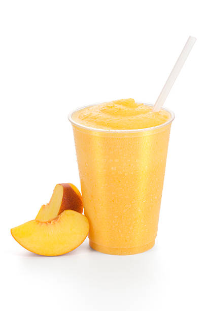 A cold refreshing peach smoothie with two peach slices on the side.