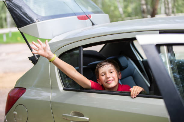 istock A cheerful, joyful child in a car while traveling waves his hand. 1713546376