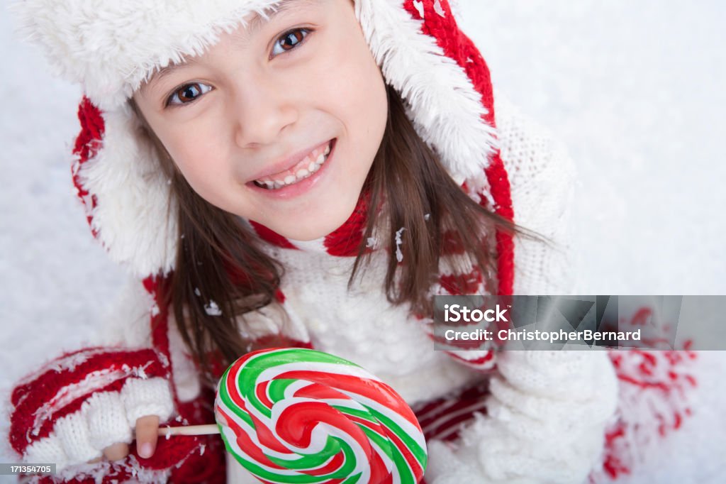 Giovane ragazza seduta nella neve con dolciumi - Foto stock royalty-free di 6-7 anni