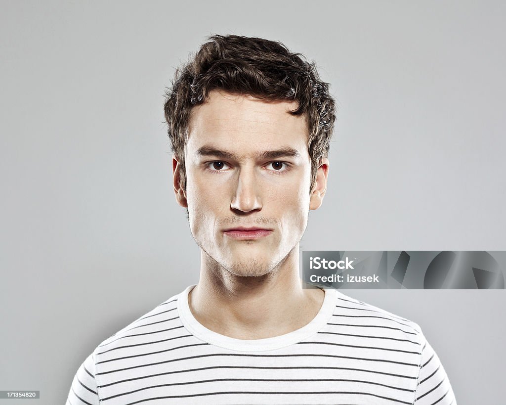 Young Male Portrait Portrait of confident young man looking at the camera. Studio shot, grey background. Young Men Stock Photo