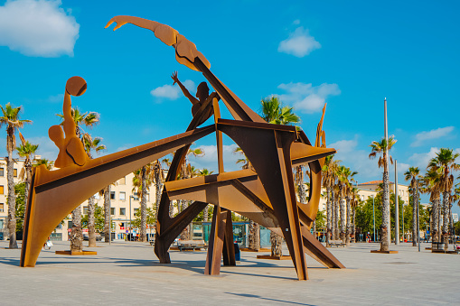 Barcelona, Spain - July 27, 2023: A view of Placa del Mar square in La Barceloneta, Barcelona, Spain, highlighting the Homenatge a la Natacio sculpture, tribute to swimming as sport, in the foreground