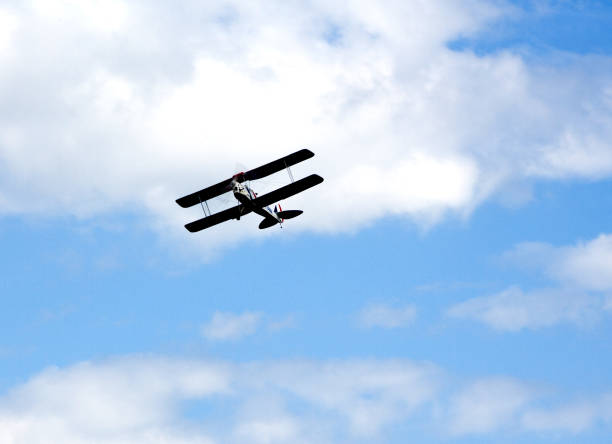 Red biplane with one propeller flying in a blue sky. Shot from below / front.