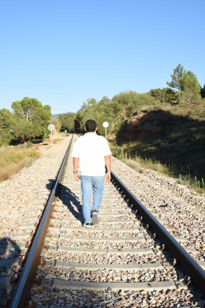istock Lonely man walking on the train tracks in the mountains 1713557435