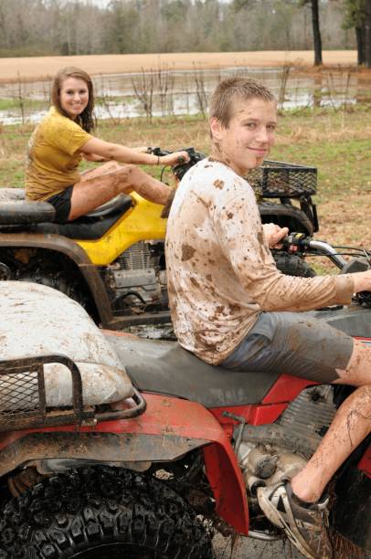 Kids sitting on muddy four wheelers