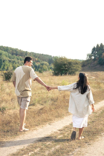 istock A man and a woman walk into a field holding hands. 1713567460