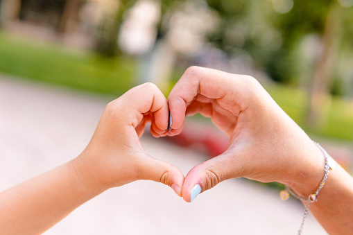 Two little girls make shape of heart with hands,close up