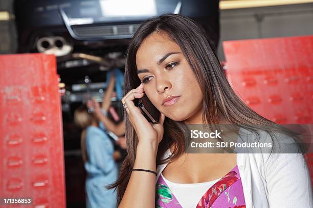 Concerned Woman On Phone At Auto Body Shop Stock Photo - Download Image Now - Adult, Asian and Indian Ethnicities, Assistance