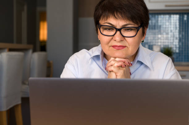 istock senior woman sitting at the table at home working using computer laptop with a puzzled face.remote work. lmoderan technologies usage 1713568605