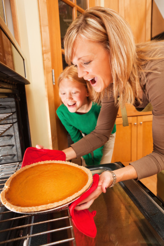 Subject: Mother and child preparing pumpkin pie together fresh from the kitchen oven.