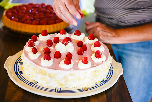 Decorating delicious raspberry cream cake kitchen woman hand