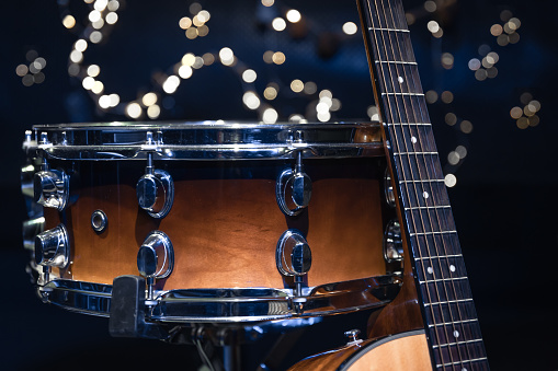 Close-up, snare drum and guitar on a blurred background with bokeh lights.