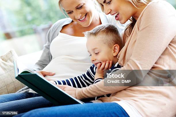 Young Family Reading Story Book Stock Photo - Download Image Now - Abdomen, Adult, Affectionate