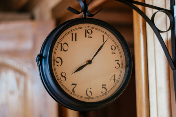 istock Round vintage clock in black metal hanging on corner mount on wooden wall. Decorative elements. 1713582264