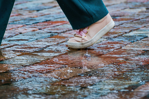 walking through a puddle in the rain. a passerby's foot on the paving stones.