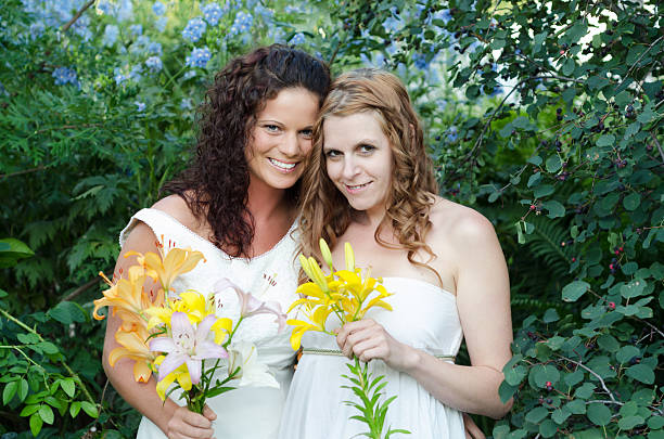 cintura arriba de dos las novias abrazándose en el jardín. - bride women standing beauty in nature fotografías e imágenes de stock