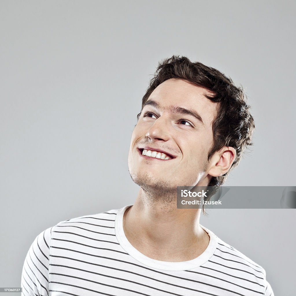 Young Male Portrait Portrait of happy young man looking up. Studio shot, grey background. Looking Up Stock Photo