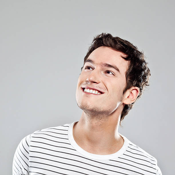 Young Male Portrait Portrait of happy young man looking up. Studio shot, grey background. cheesy grin stock pictures, royalty-free photos & images