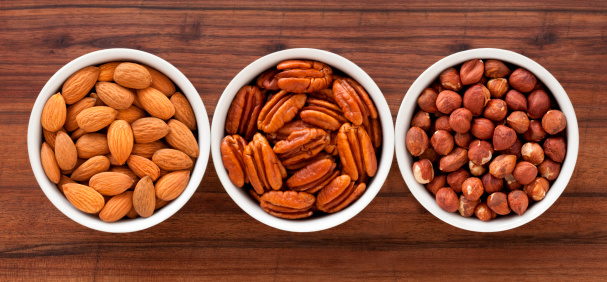 Three bowls with almonds, pecans and hazelnuts
