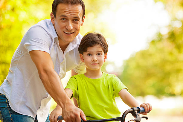 istock Father Assisting Child to ride a bicycle. 171360585
