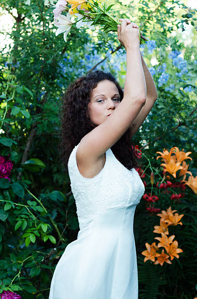 Bride threatening to wack someone with bouquet Vertical outdoor garden shot of bride with bouquet raised in both hands. wack stock pictures, royalty-free photos & images