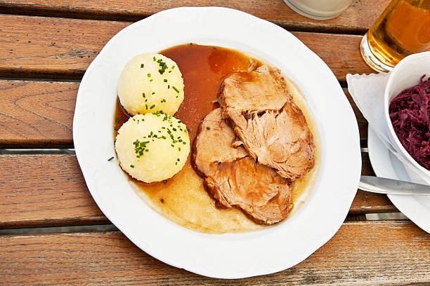 typical bavarian food, served in a restaurant in a small town in Bavaria, Germany: 2 slices of pork and dumplingd, with a side dish of red cabbage, focus on meat