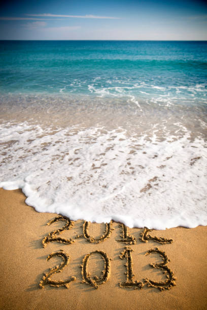 2013 und 2012 schriftliche in sand und wellen - 2013 beach new years eve new years day stock-fotos und bilder