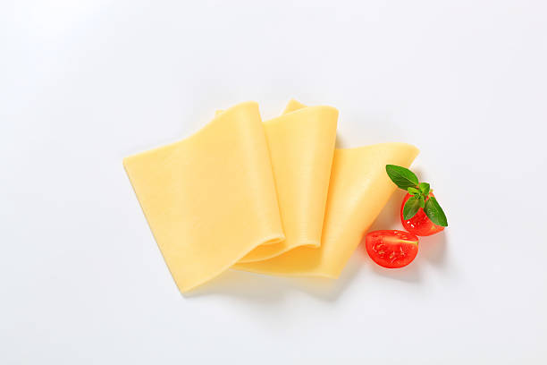 Three yellow slices of cheese with cherry tomatoes stock photo