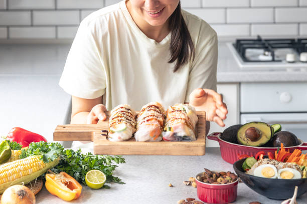 istock A young woman with spring rolls in rice paper in the kitchen. 1713616437