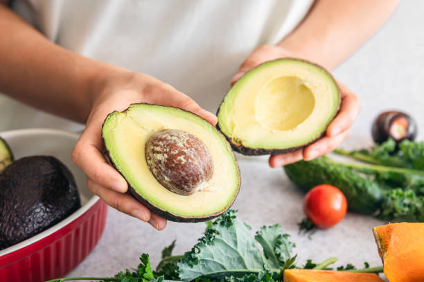 istock Avocado halves in a female hand in the kitchen. 1713616447